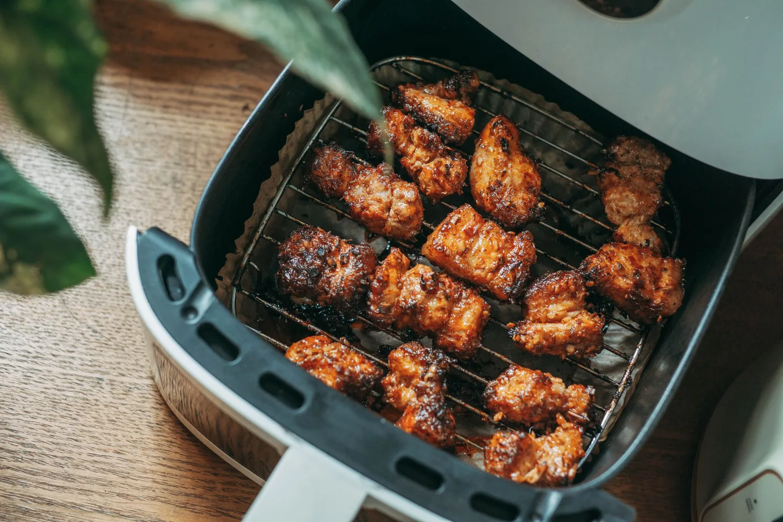 An air-fryer basket pulled out, holding cooked chicken pieces arranged in a single layer on the basket rack